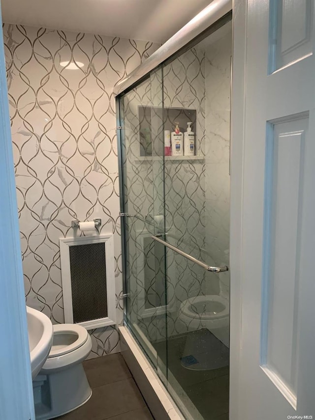 bathroom featuring heating unit, a shower with door, tile patterned flooring, and toilet