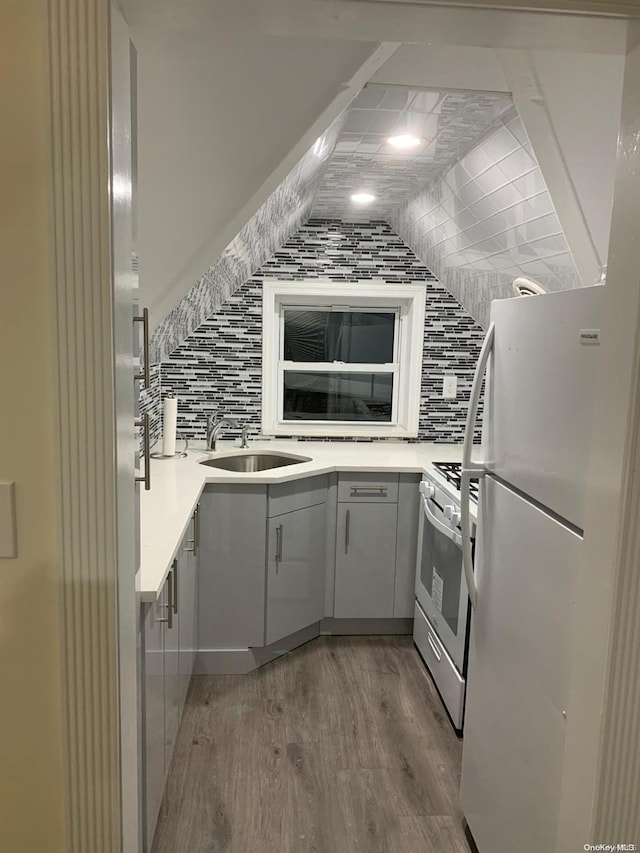 kitchen featuring sink, tasteful backsplash, white refrigerator, wood-type flooring, and high end range