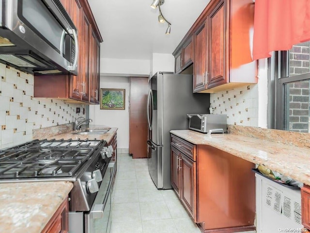 kitchen featuring light stone countertops, tasteful backsplash, stainless steel appliances, sink, and light tile patterned floors