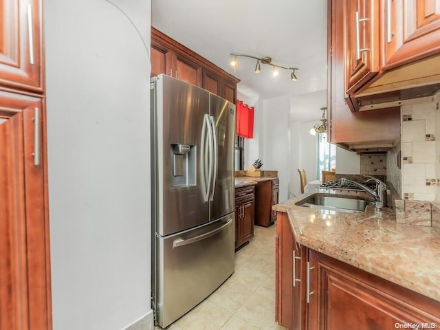 kitchen with sink, decorative backsplash, stainless steel fridge, light tile patterned floors, and light stone counters