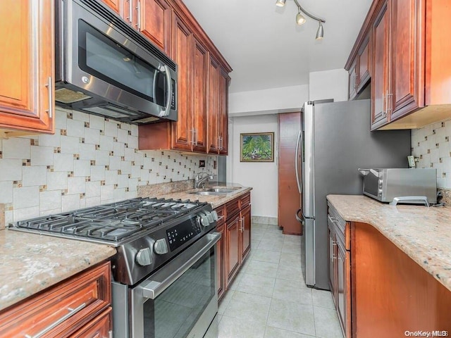 kitchen featuring backsplash, light stone countertops, sink, and appliances with stainless steel finishes