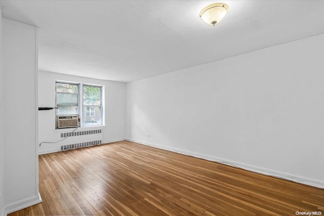 unfurnished living room featuring radiator heating unit and hardwood / wood-style flooring