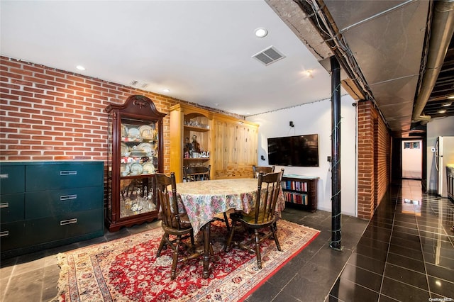 dining area with brick wall and dark tile patterned flooring