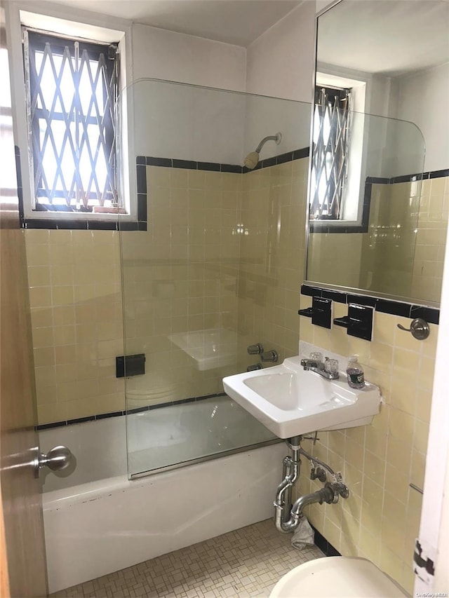 full bathroom with tiled shower / bath, sink, tile patterned flooring, toilet, and tile walls