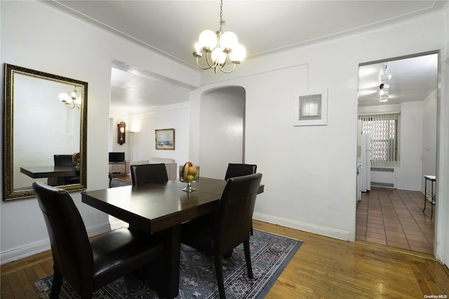 dining space with wood-type flooring and an inviting chandelier