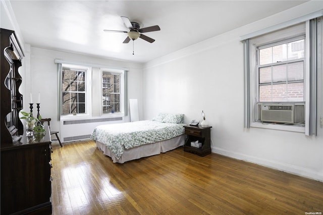 bedroom with radiator, ceiling fan, dark hardwood / wood-style flooring, cooling unit, and ornamental molding