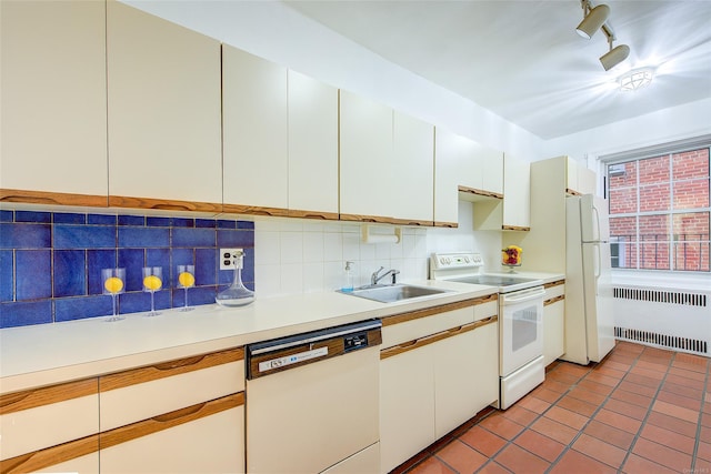 kitchen with white appliances, radiator heating unit, a sink, light countertops, and backsplash