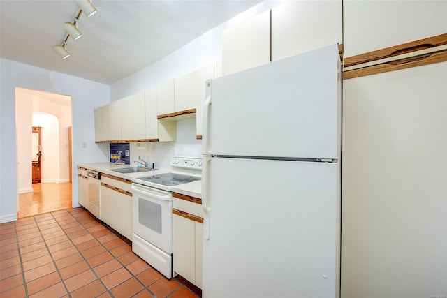 kitchen with light countertops, decorative backsplash, arched walkways, white appliances, and a sink