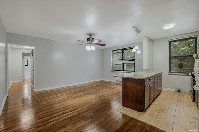 kitchen with pendant lighting, light hardwood / wood-style flooring, ceiling fan, light stone counters, and kitchen peninsula