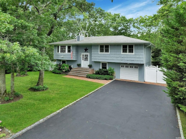 raised ranch featuring a garage and a front lawn