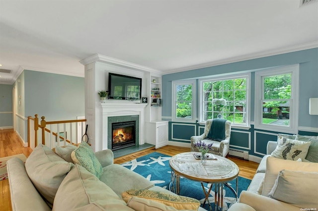 living room with light hardwood / wood-style flooring, a baseboard radiator, built in features, and ornamental molding