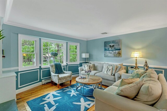 living room featuring ornamental molding, light hardwood / wood-style floors, and a baseboard heating unit