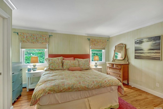 bedroom featuring light wood-type flooring, multiple windows, and crown molding