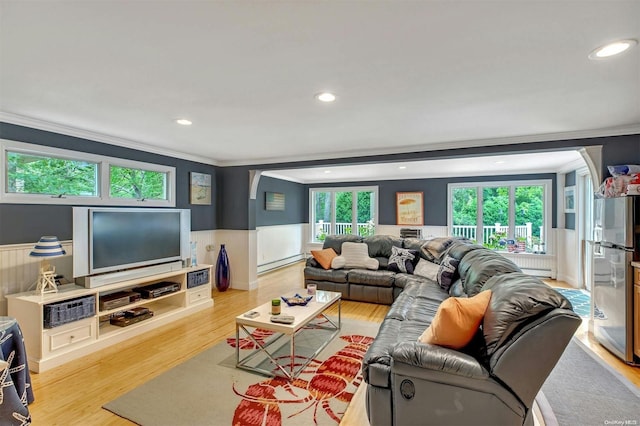 living room with light hardwood / wood-style floors, baseboard heating, plenty of natural light, and crown molding