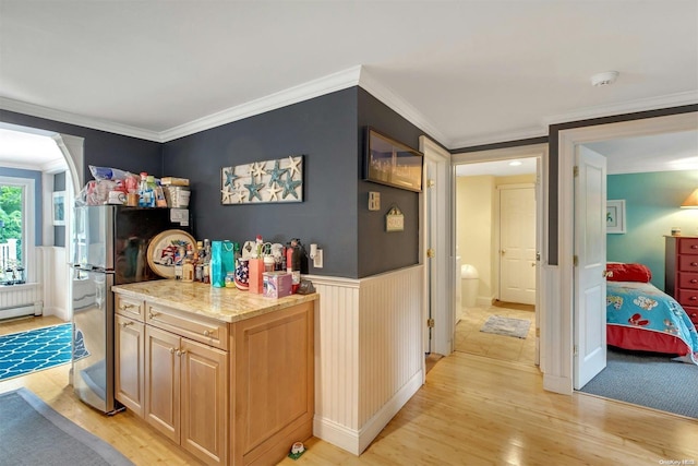 kitchen with stainless steel refrigerator, light brown cabinets, light stone counters, light hardwood / wood-style floors, and ornamental molding