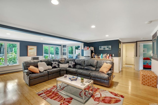 living room with a wealth of natural light, crown molding, a baseboard heating unit, and light wood-type flooring