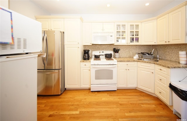 kitchen with white appliances, light hardwood / wood-style floors, tasteful backsplash, and sink