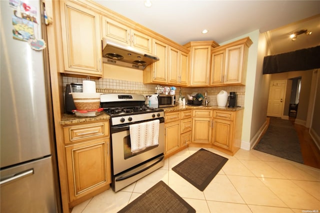 kitchen with backsplash, light stone counters, light tile patterned floors, and stainless steel appliances