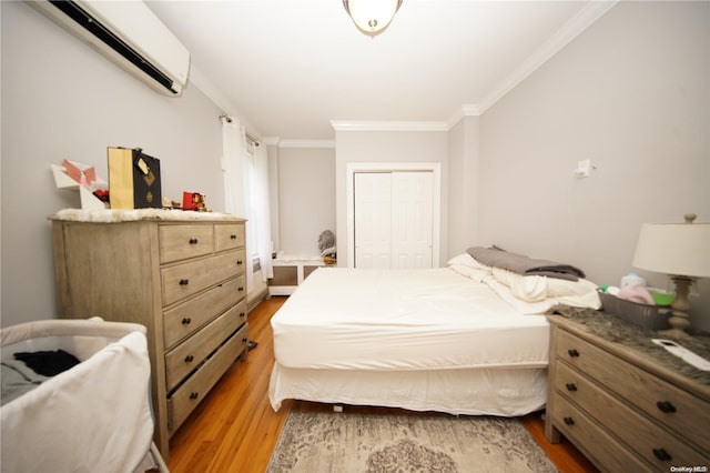 bedroom with hardwood / wood-style floors, a wall unit AC, a closet, and crown molding