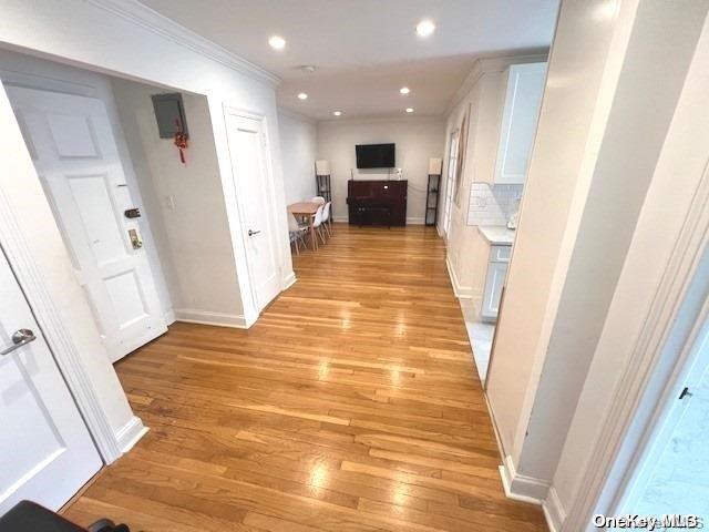 corridor featuring crown molding and light hardwood / wood-style flooring