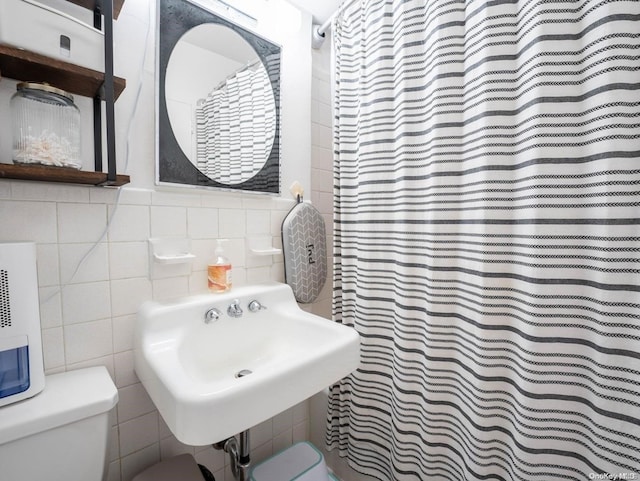 bathroom featuring a shower with curtain, sink, tile walls, and toilet