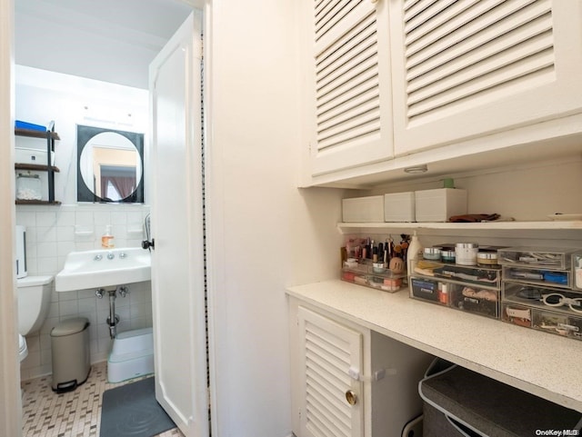 interior space featuring tile patterned flooring, tile walls, and sink