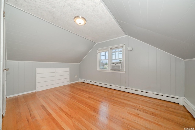 additional living space with a textured ceiling, cooling unit, baseboard heating, hardwood / wood-style floors, and lofted ceiling