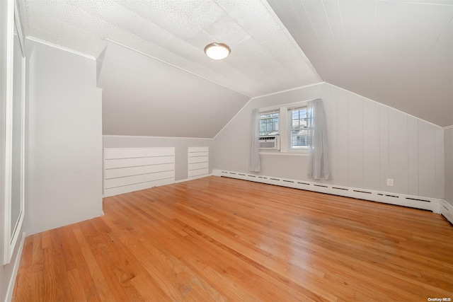 additional living space featuring hardwood / wood-style flooring, lofted ceiling, a textured ceiling, and a baseboard heating unit