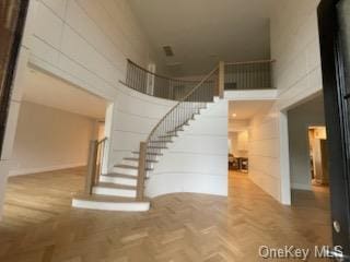 stairway featuring parquet flooring and a high ceiling