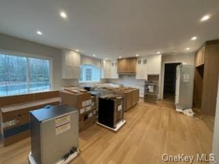 kitchen with oven, a kitchen island, light wood-type flooring, and white cabinetry