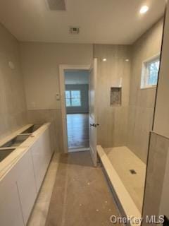 bathroom with a tile shower and a wealth of natural light