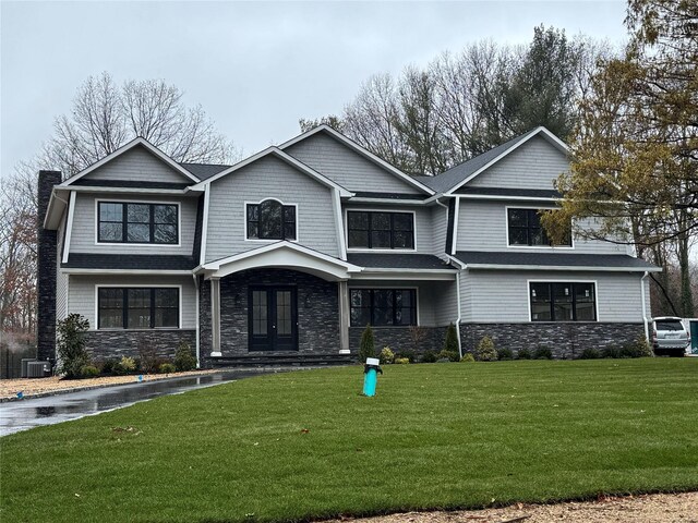 view of front of home with a front yard, stone siding, a chimney, and french doors