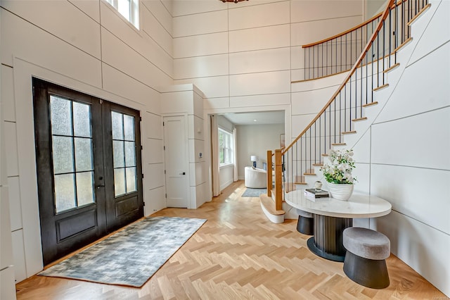 entryway featuring french doors, stairway, and a high ceiling