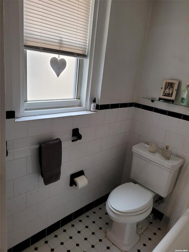 bathroom featuring toilet and tile walls