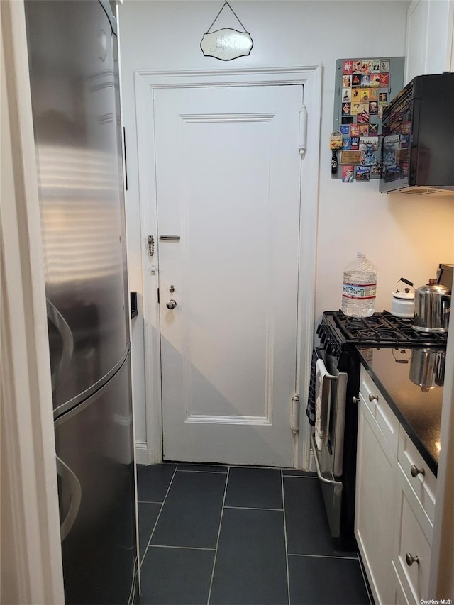 kitchen featuring stainless steel gas stove, white cabinetry, and dark tile patterned floors