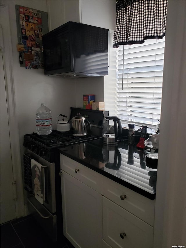 434 E 52nd St Unit 9A, New York Manhattan, NY 10022 - kitchen with gas stove, white cabinetry, and dark countertops