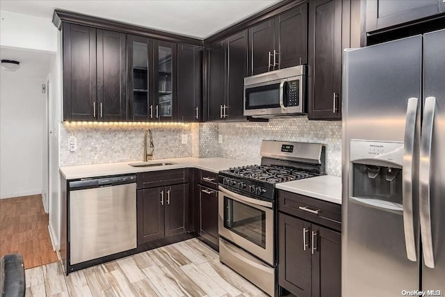 kitchen with sink, decorative backsplash, dark brown cabinets, light hardwood / wood-style floors, and stainless steel appliances