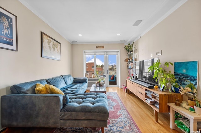 living room with light hardwood / wood-style floors and crown molding