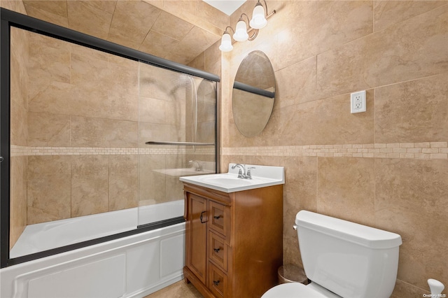 full bathroom with vanity, toilet, shower / bath combination with glass door, and tile walls