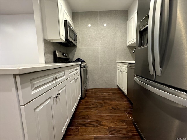 kitchen featuring dark wood-type flooring, white cabinets, stainless steel appliances, and tile walls