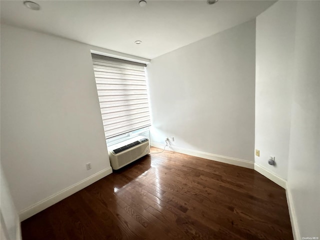 unfurnished room featuring dark hardwood / wood-style flooring and a wall mounted AC