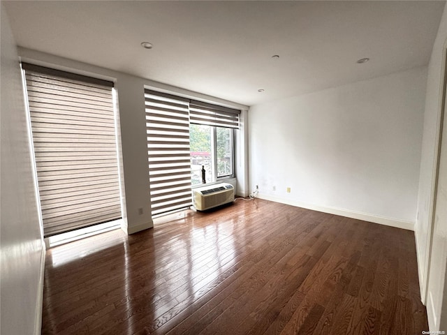 empty room featuring an AC wall unit and dark hardwood / wood-style floors