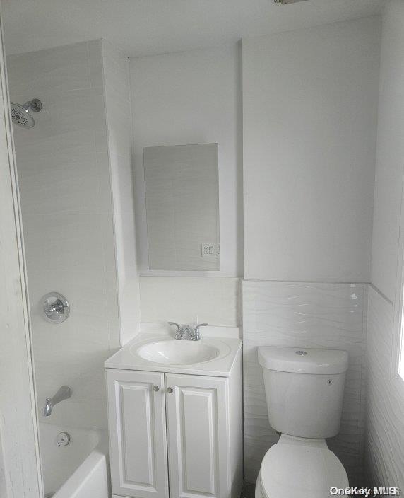 full bathroom with vanity, toilet, tile walls, and tiled shower / bath combo