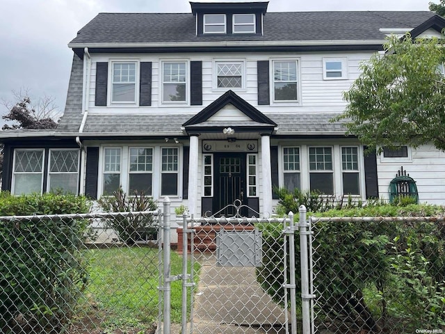 view of front of property with a fenced front yard, roof with shingles, and a gate