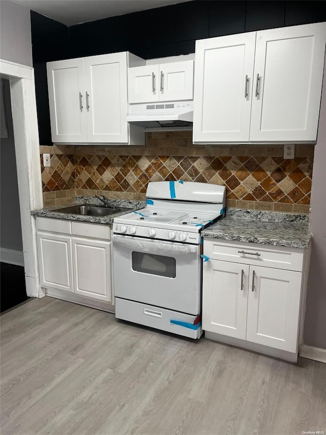 kitchen with under cabinet range hood, light wood-style flooring, white gas stove, and white cabinets