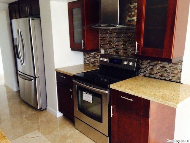 kitchen featuring decorative backsplash, appliances with stainless steel finishes, and wall chimney range hood