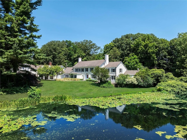 rear view of property with a lawn and a water view