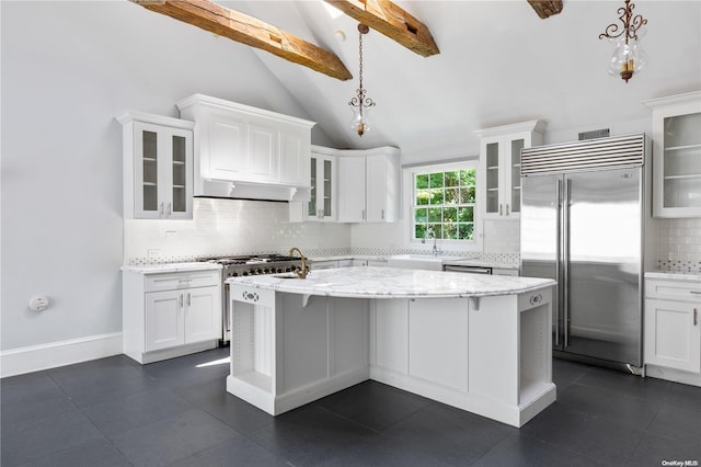 kitchen with pendant lighting, tasteful backsplash, high end appliances, and an island with sink