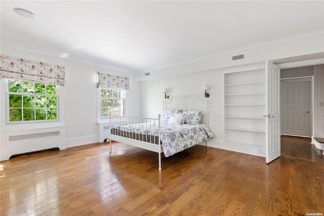 bedroom with wood-type flooring, radiator heating unit, and ornamental molding