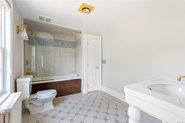 bathroom with toilet, shower / bath combination with glass door, and radiator